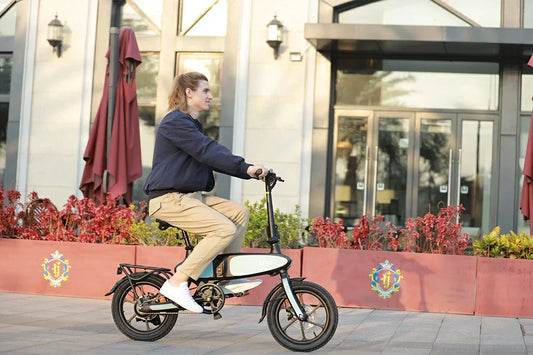 Side lifestyle shot of man riding compact white DYU C2 foldable electric bike on modern building plaza.