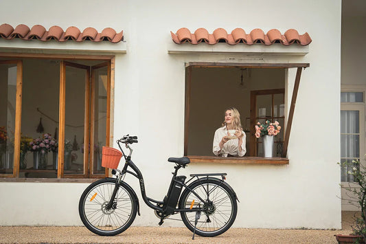 Cozy countryside lifestyle shot of matte black DYU C6 step-through city electric bike parked outside cream floral café with woman holding coffee at service window.